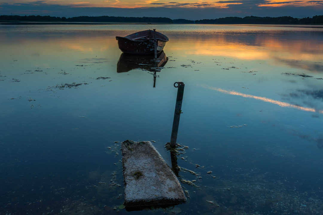 Beautiful lake sunset with fisherman boat