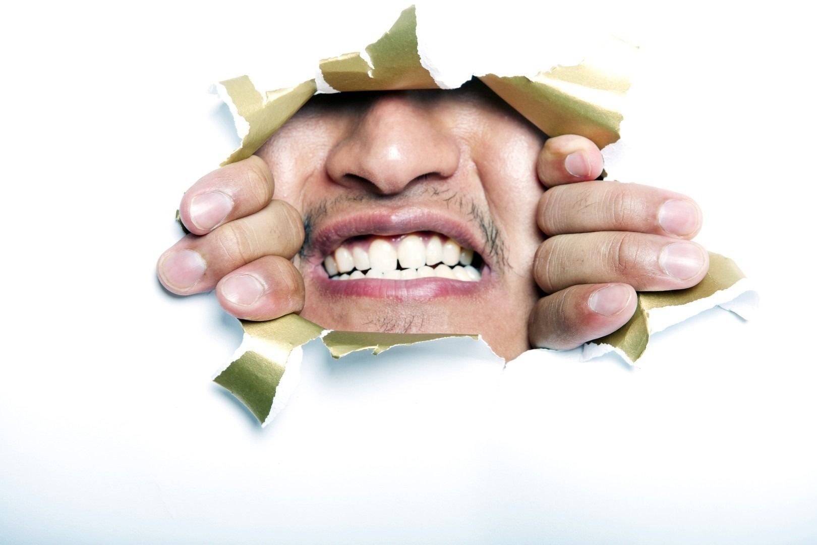 Young Korean man looking through ripped paper hole