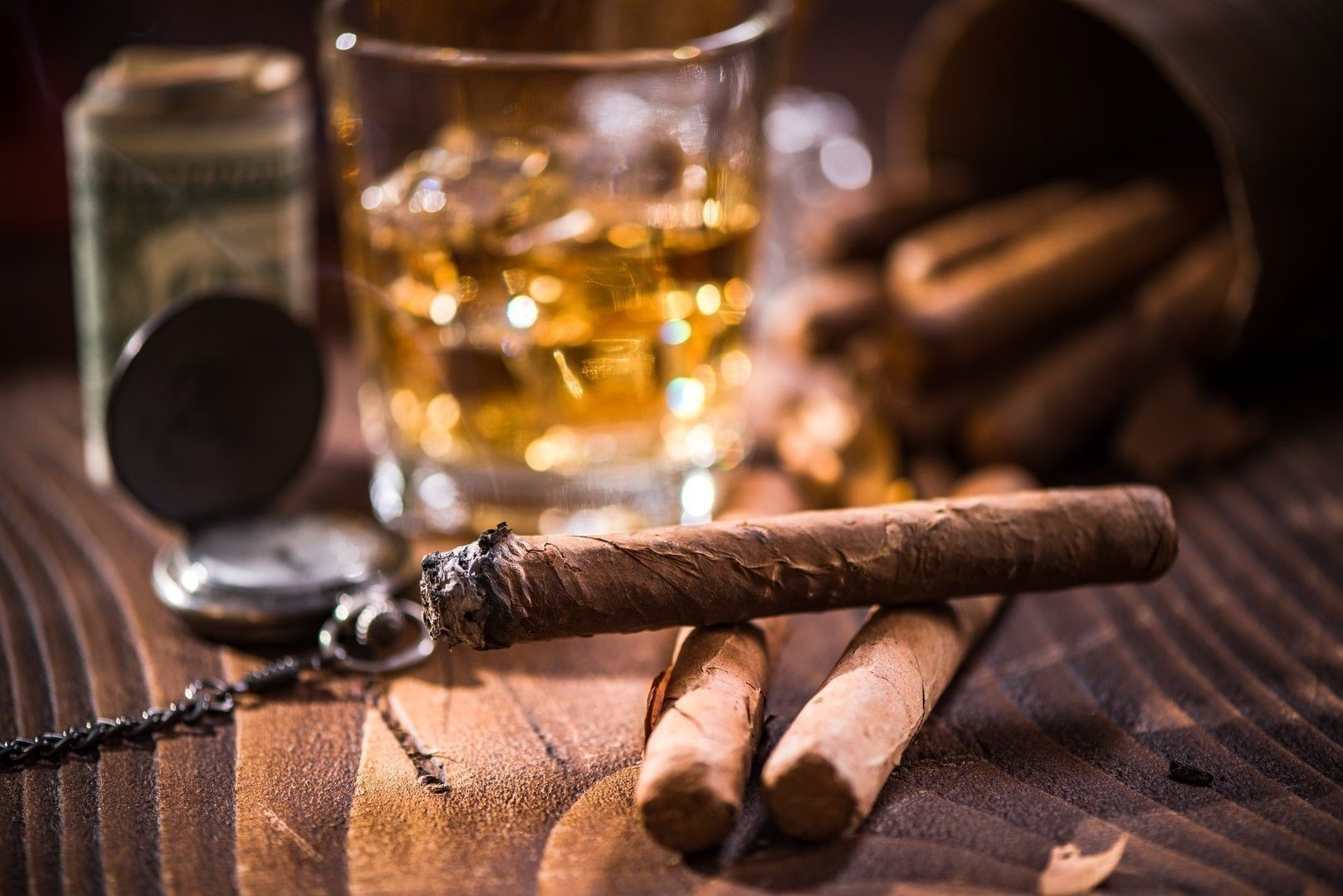 Glas with Whiskey over ice cubes and cuban cigar