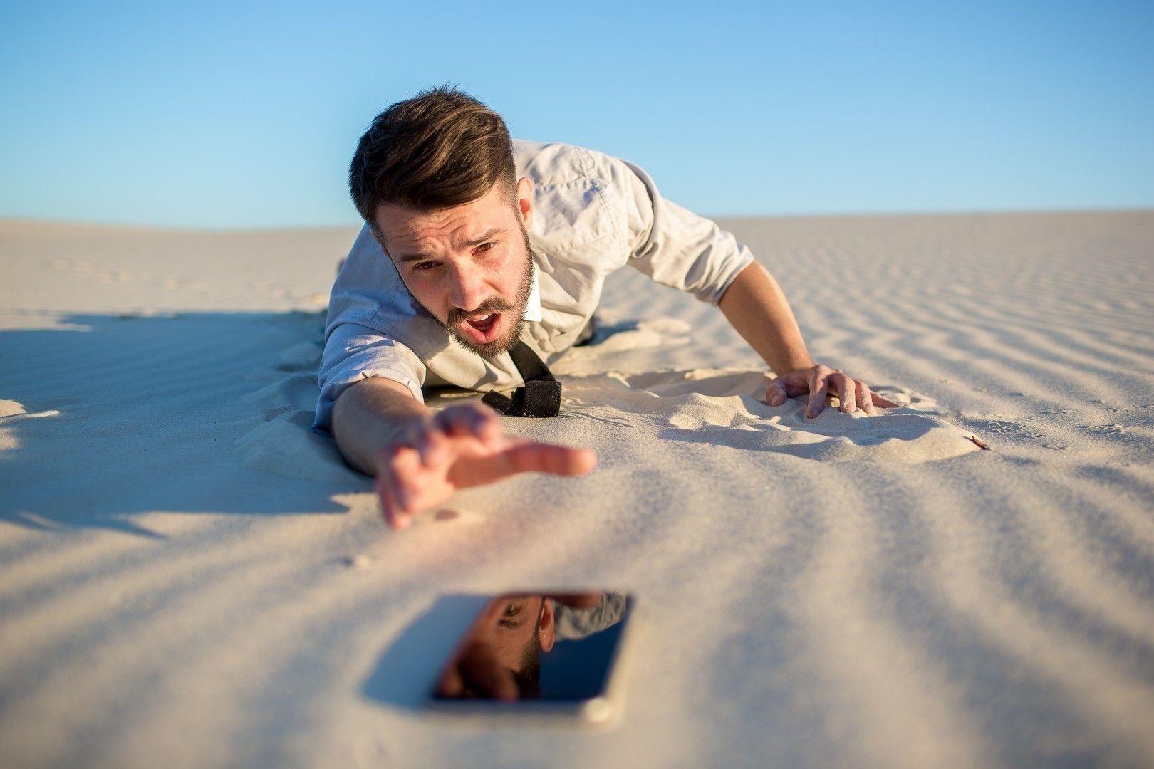 Poor signal. businessman searching for mobile phone signal in desert