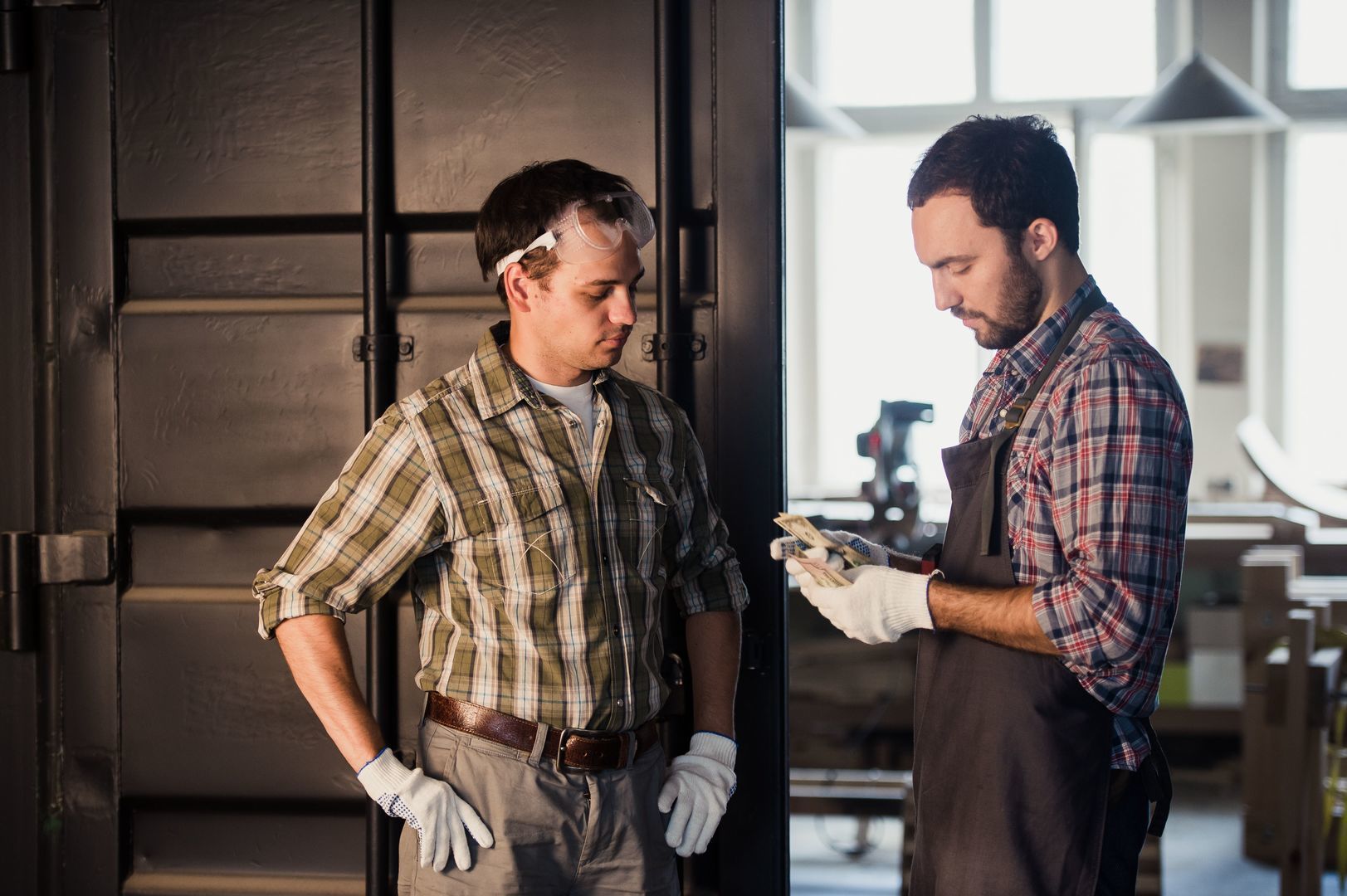 Young carpenter gets money for his work in workshop carpentry