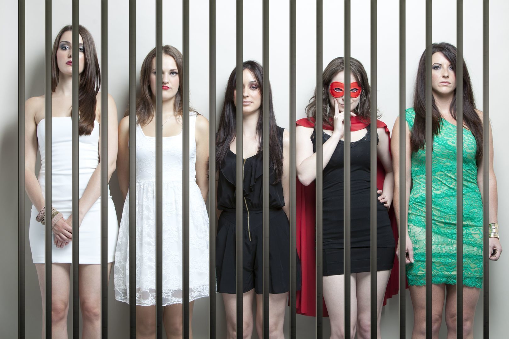 Woman in superhero costume with female friends standing behinds prison bars