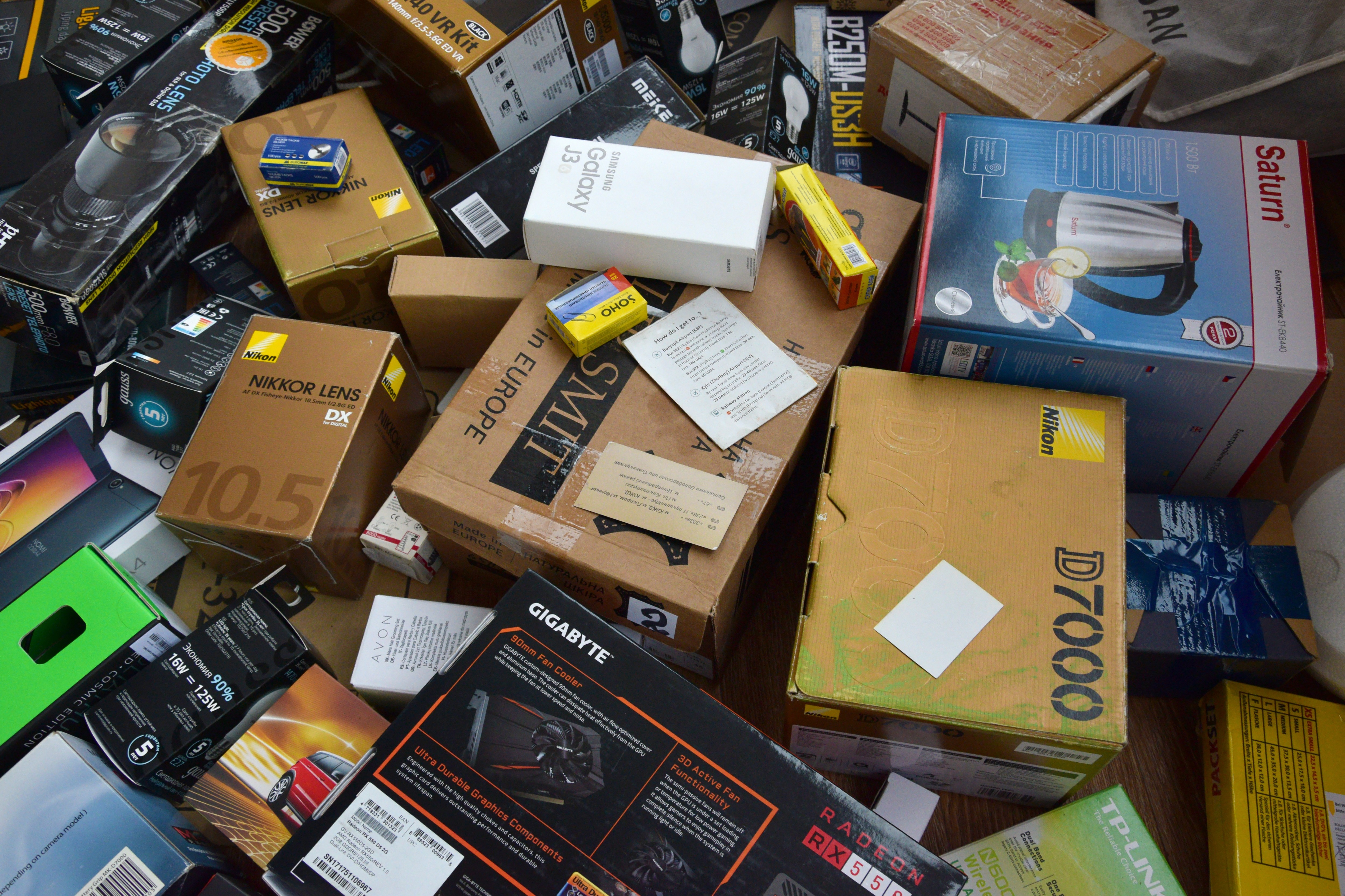 Big pile of many cardboard boxes from electronic products of famous manufacturers. Disposable wrappings of domestic use goods. Waste paper recycling