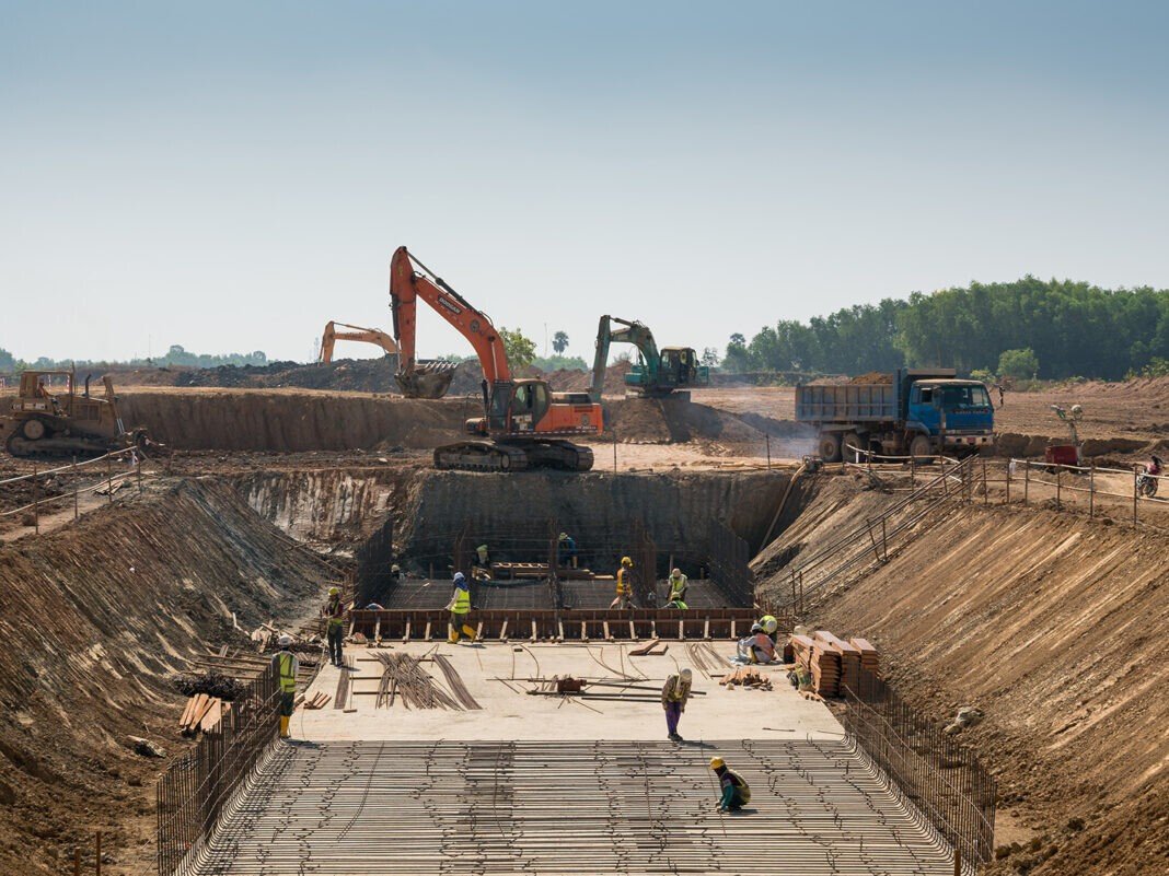 Close shot of heavy machines and construction workers working on a building