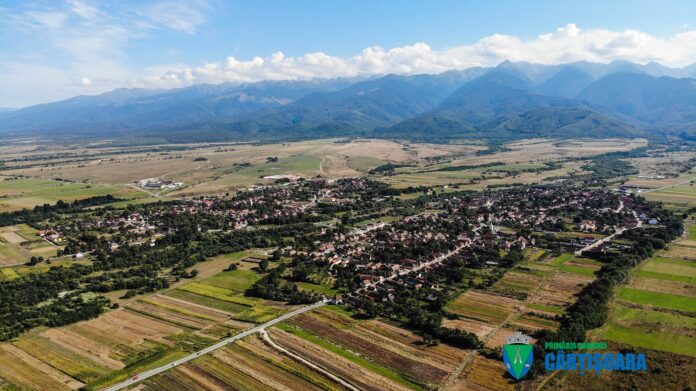 Panou informativ și oameni la o ședință despre terenuri agricole Cârțișoara