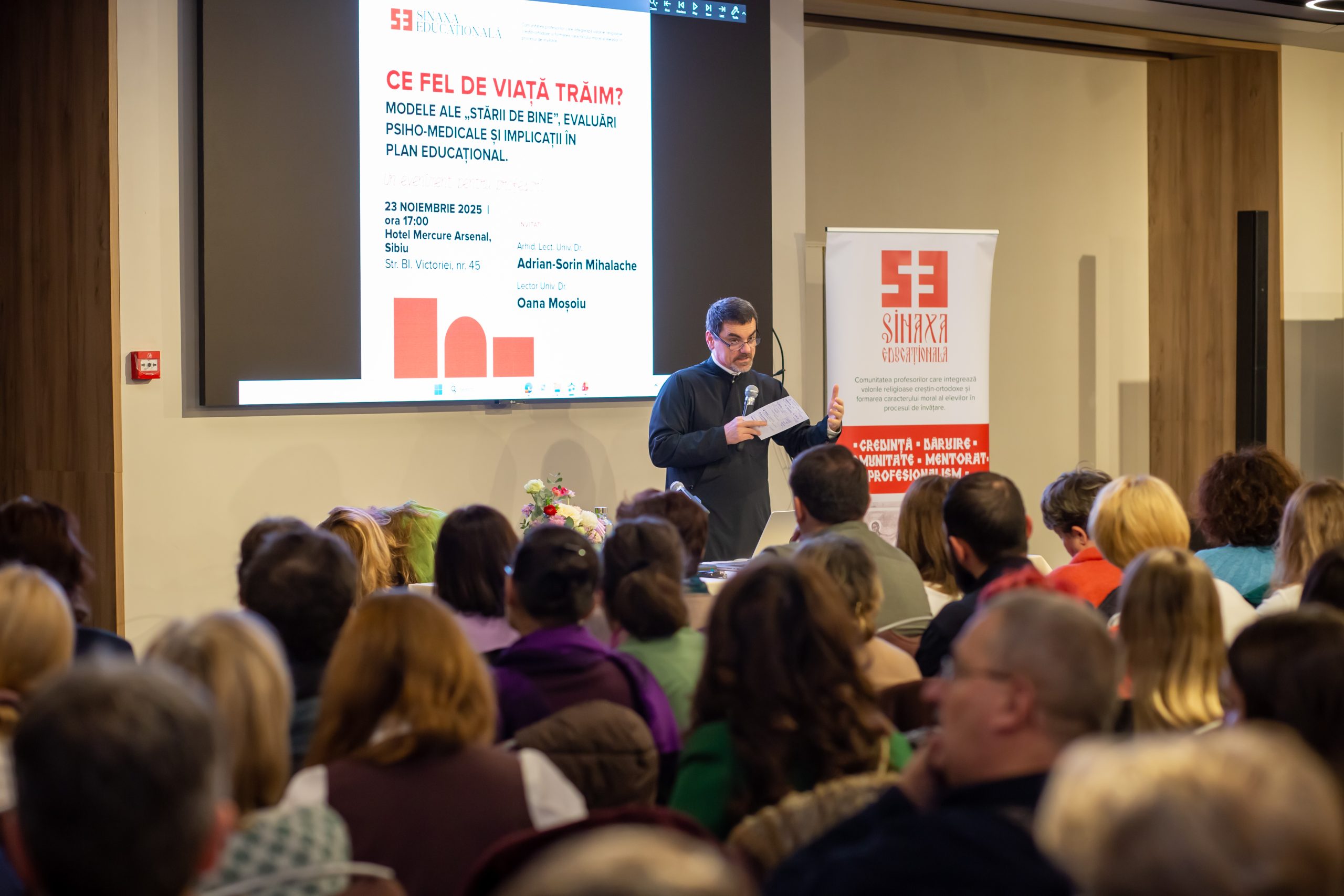 Profesori din Sibiu participă la o conferință despre starea de bine în educație, ascultând cu atenție un prezentator.
