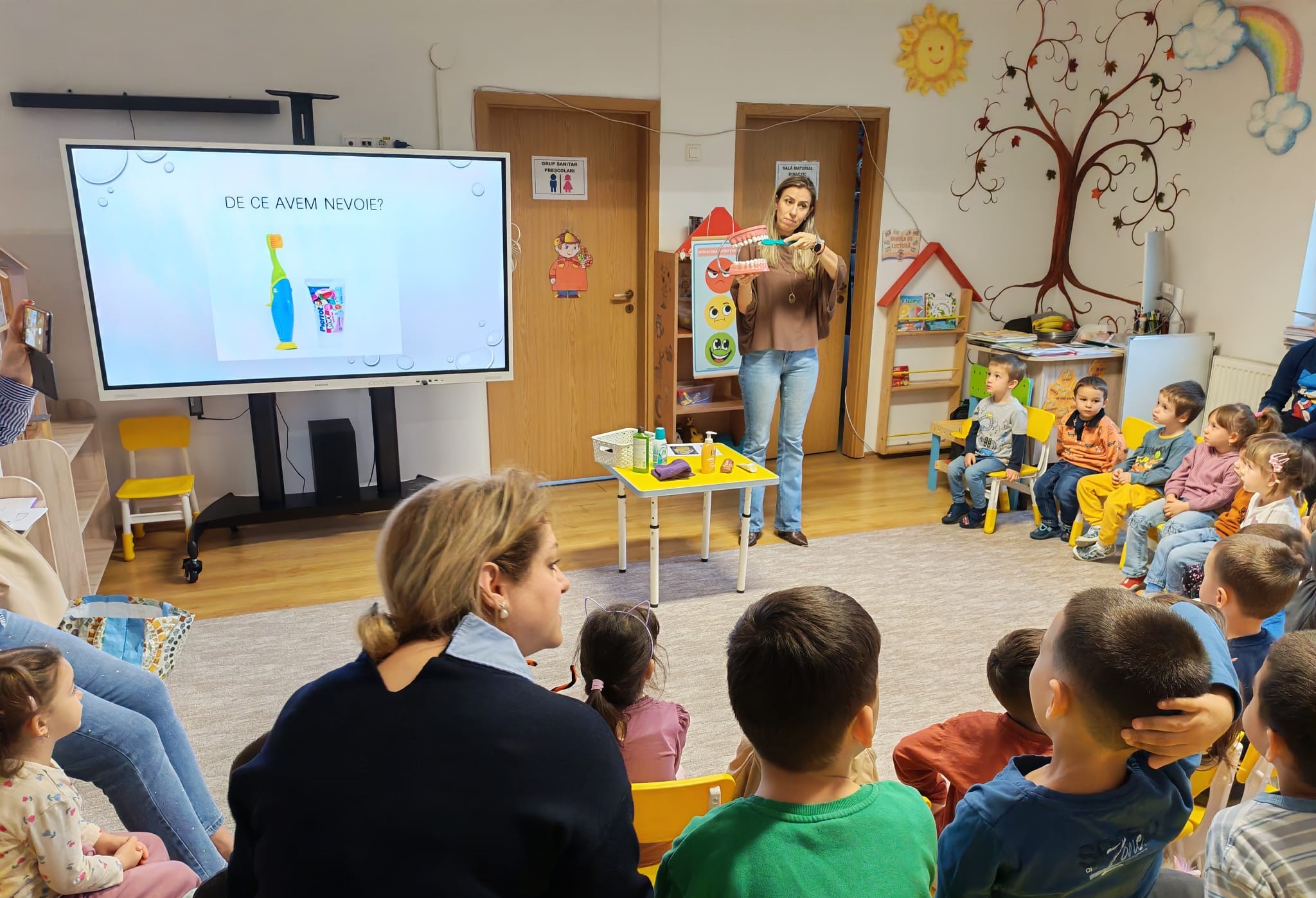 Grupa de copii fericiți ascultă cu atenție lecția despre igiena orală și dințișori sănătoși.