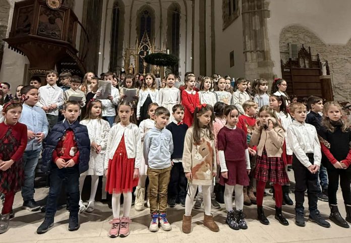 Copii cu costume tradiționale germane cântând colinde de Crăciun în fața publicului.