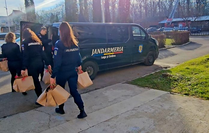 Un jandarm din Sibiu în uniformă și un coleg costumat ca Moș Crăciun pregătesc cadourile pentru copii