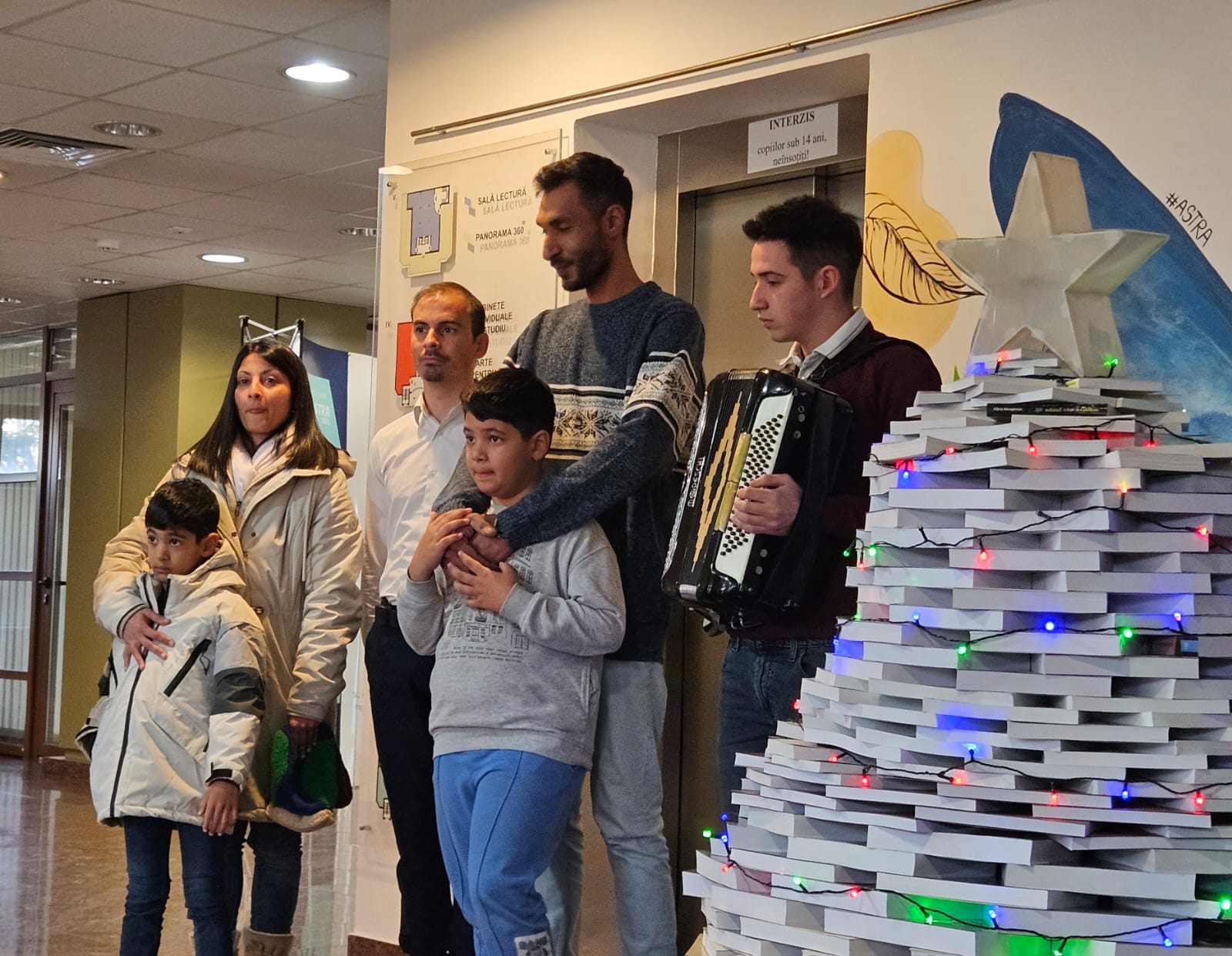 Publicul și copiii ascultă emoționați colindele tradiționale la Biblioteca ASTRA Sibiu.