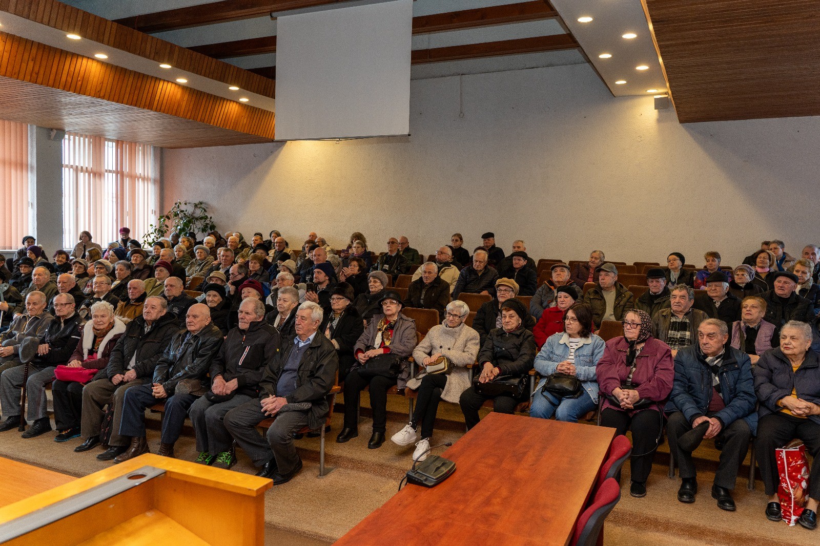 Senior de 80 de ani în Medieș primind o diplomă aniversară de la un oficial local.