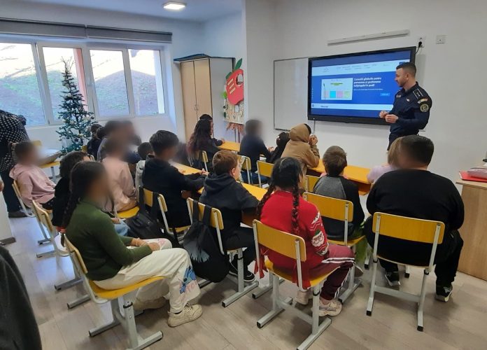 Polițiști sibieni vorbesc cu elevii în curtea școlii pentru un mediu mai sigur.