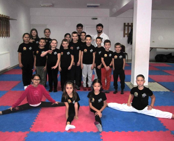 Copii din comunitate în uniforme de taekwon-do, pregătiți pentru antrenament în sala din Turnu Roșu.