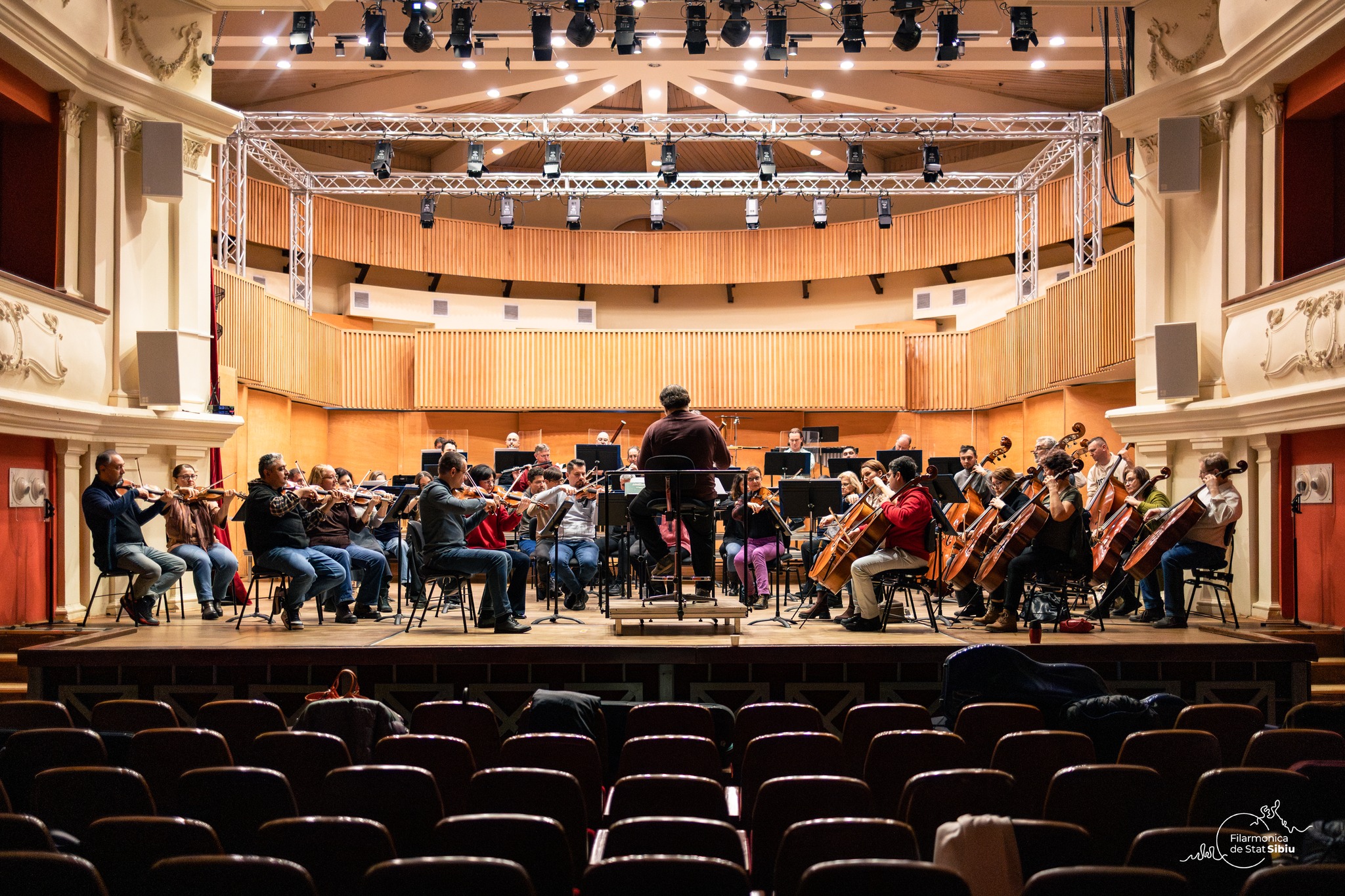 Dirijorul și orchestra filarmonică în timpul unui concert simfonic la Filarmonica Sibiu