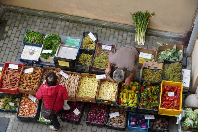 Angajat examinează produsele agricole locale disponibile la „Piața la birou” din Sibiu.