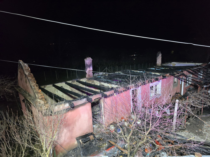 Echipaj de pompieri luptând cu flăcările puternice la casa din Blăjel, cu jet de apă îndreptat spre acoperiș.