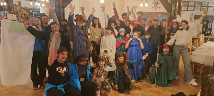 Participanții la tabăra bilingvă de iarnă „Ski-Sky” în fața cabanei, cu munții în fundal