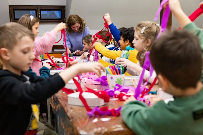 Copii creativă la atelierele creative Gong Sibiu, făcând păpuși inimoare din materiale colorate.