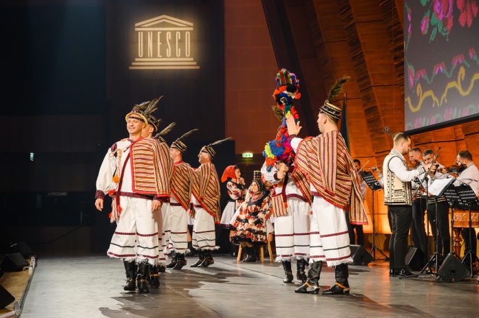 Junii Sibiului călări pe cai în ceremonial tradițional, purtând costume populare ornamentate.