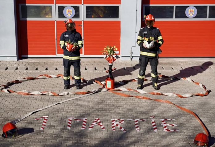Pompier ISU Sibiu în uniformă de ceremonie, ținând un mărțișor și flori pentru 1 Martie.