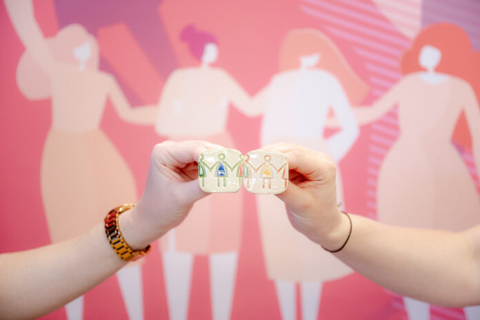 Mâini unite ale unor femei care sparg un lanț, simbol al eliberării și a solidarității.