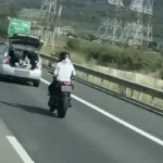 Trei tineri filmând o cursă periculoasă de pe autostradă A1 din portbagajul unei mașini în mișcare.