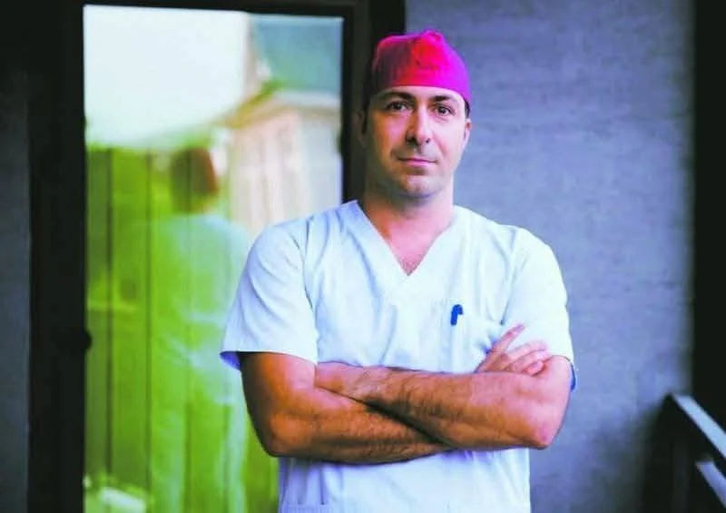 Prof. univ. dr. Ciprian Tănăsescu chirurg în cabinetul său medical, privind cu dedicare.