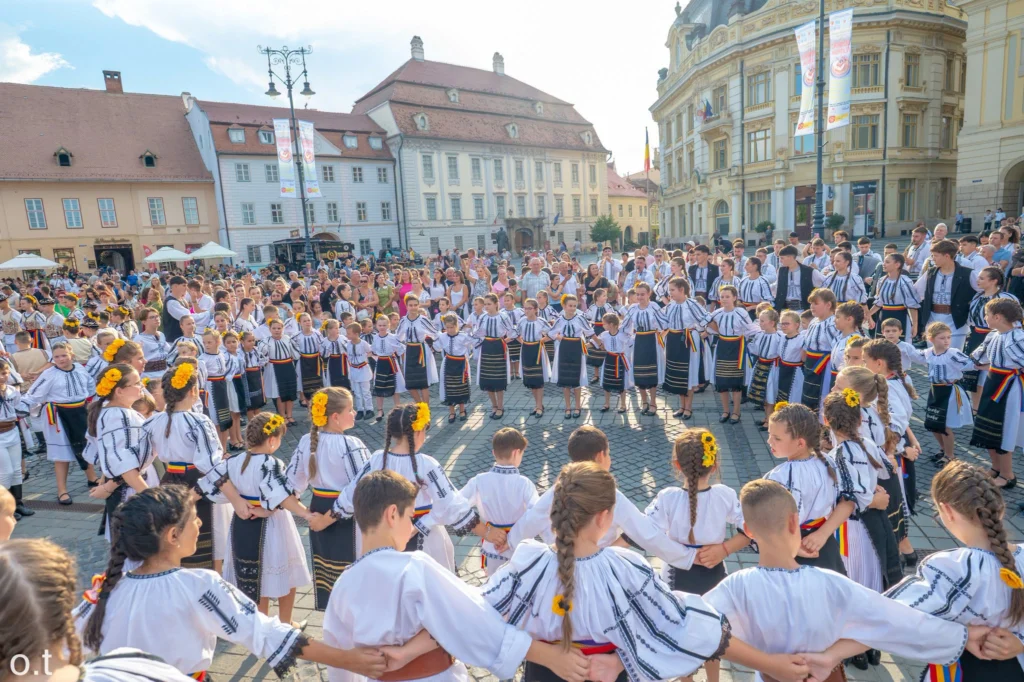 Copii îmbrăcați în costume regionale minunate, participând la deschiderea spectacolului Cântecele Munților.