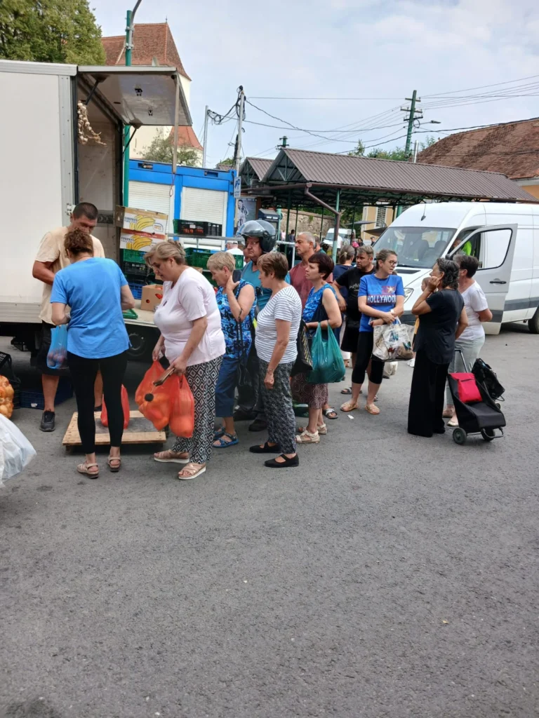 Camion încărcat cu marfă de producători români la piața din Cisnădie, clienți în jur