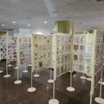 Vizitatori admirând expoziția filatelică Sibiu, cu vitrine pline cu timbre istorice.