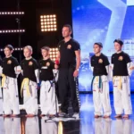 Ricky, campion la taekwon-do, în poza de campion, purtând un kimou și centura neagră în timpul antrenamentului.
